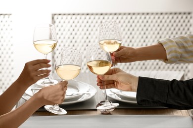 Photo of People clinking glasses of wine indoors, closeup