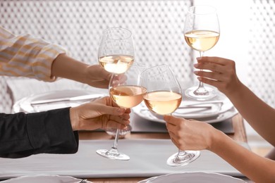 Photo of People clinking glasses of wine indoors, closeup