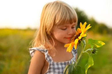 Photo of Little girl with sunflower at meadow. Child enjoying beautiful nature