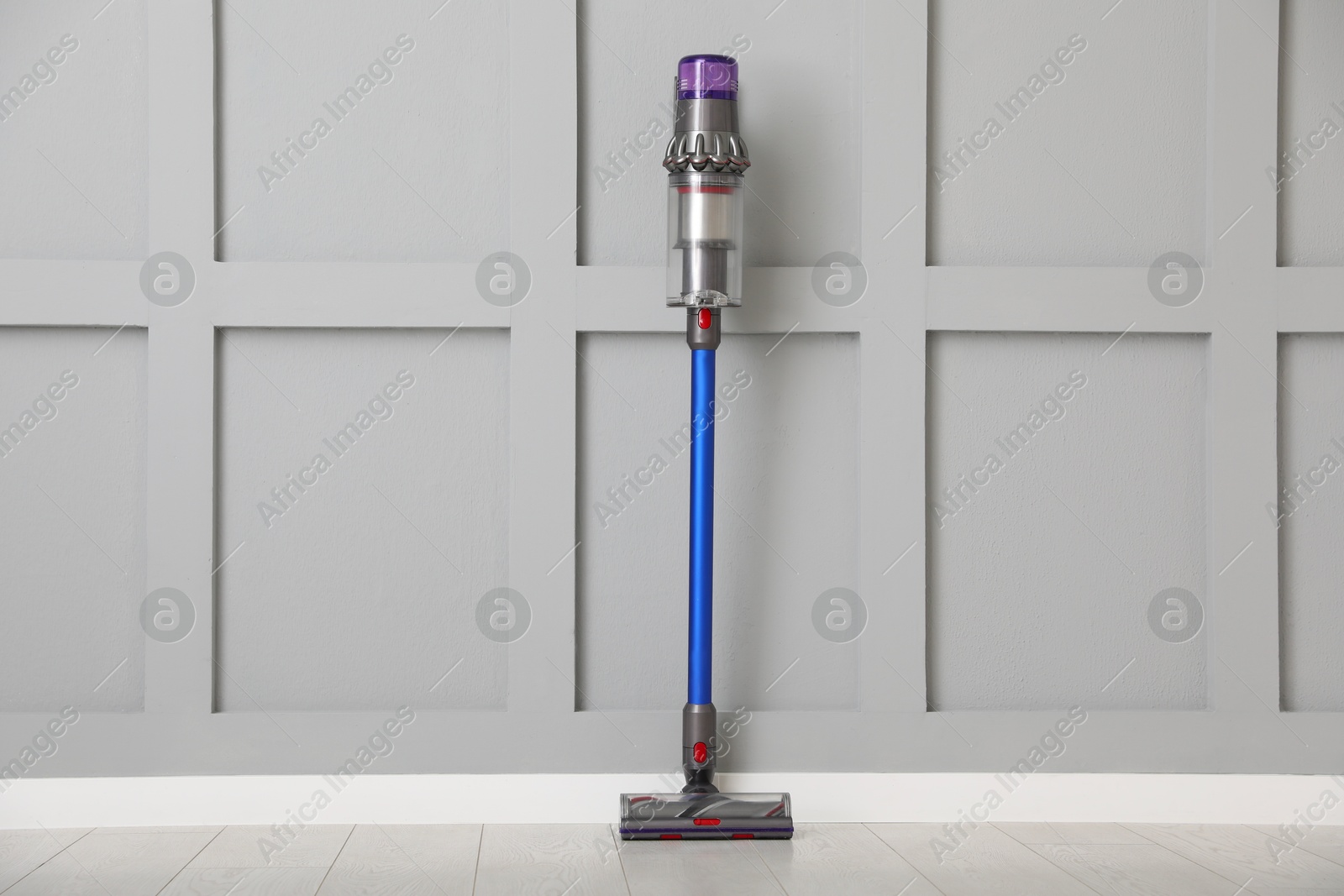 Photo of One cordless vacuum cleaner near grey wall indoors