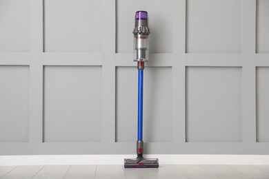 Photo of One cordless vacuum cleaner near grey wall indoors