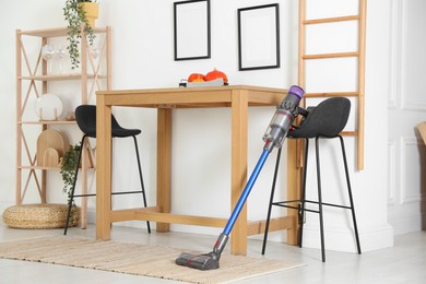 Photo of One cordless vacuum cleaner leaning on stool indoors