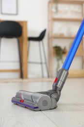 Photo of Cleaning floor with cordless vacuum cleaner indoors, closeup