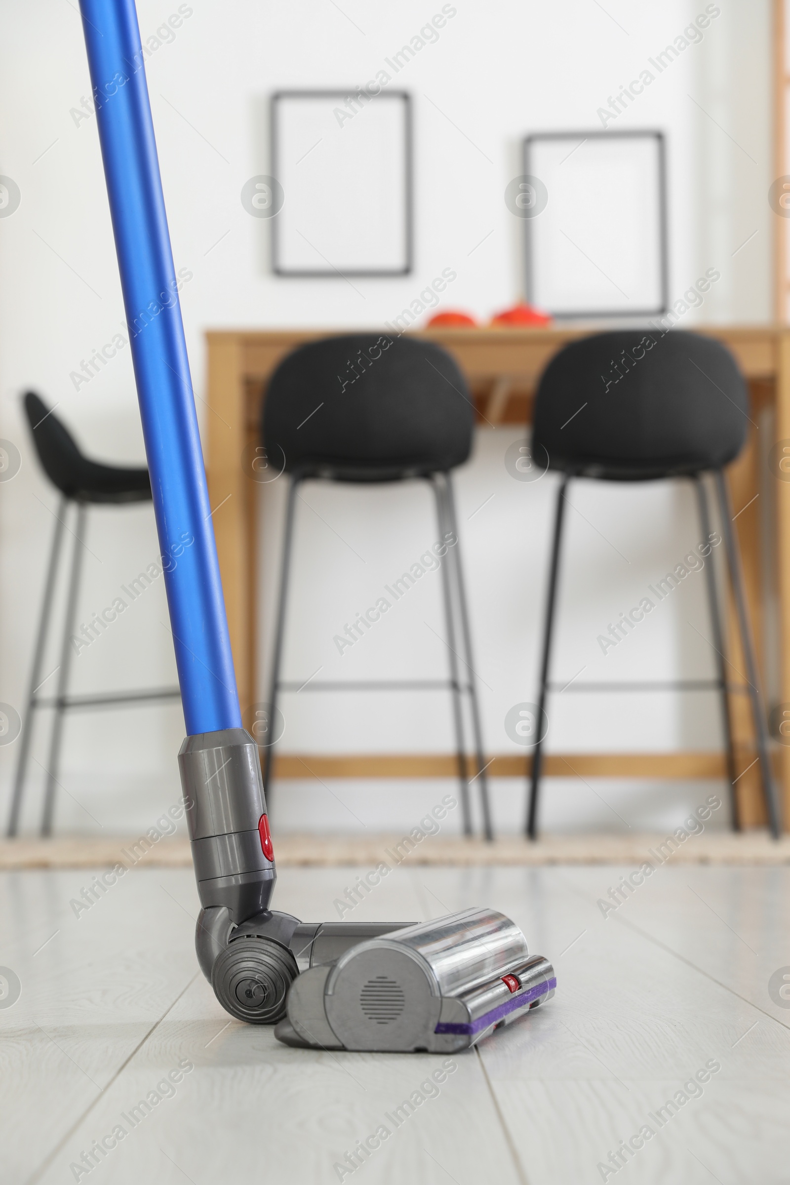 Photo of Cleaning floor with cordless vacuum cleaner indoors, closeup