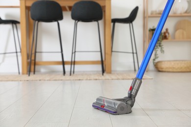 Photo of Cleaning floor with cordless vacuum cleaner indoors, closeup. Space for text