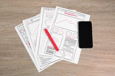 Photo of Developing UI design. Sketches of website wireframes, smartphone and felt pen on wooden table, top view