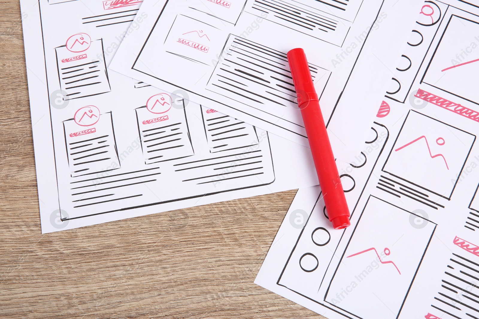 Photo of Developing UI design. Sketches of website wireframes and felt pen on wooden table, above view