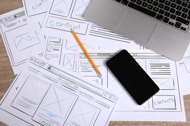 Photo of Developing UI design. Sketches of website wireframes, laptop, smartphone and pencil on wooden table, top view