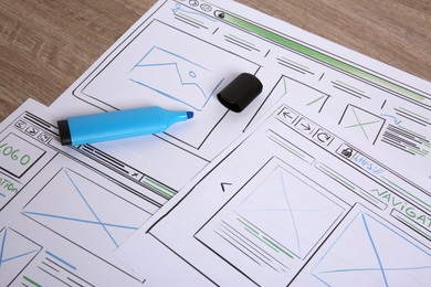 Developing UI design. Sketches of website wireframes and felt pen on wooden table, closeup