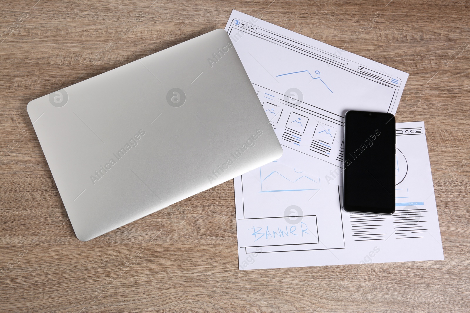 Photo of Developing UI design. Sketches of website wireframes, laptop and smartphone on wooden table, top view