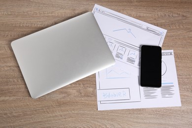 Developing UI design. Sketches of website wireframes, laptop and smartphone on wooden table, top view