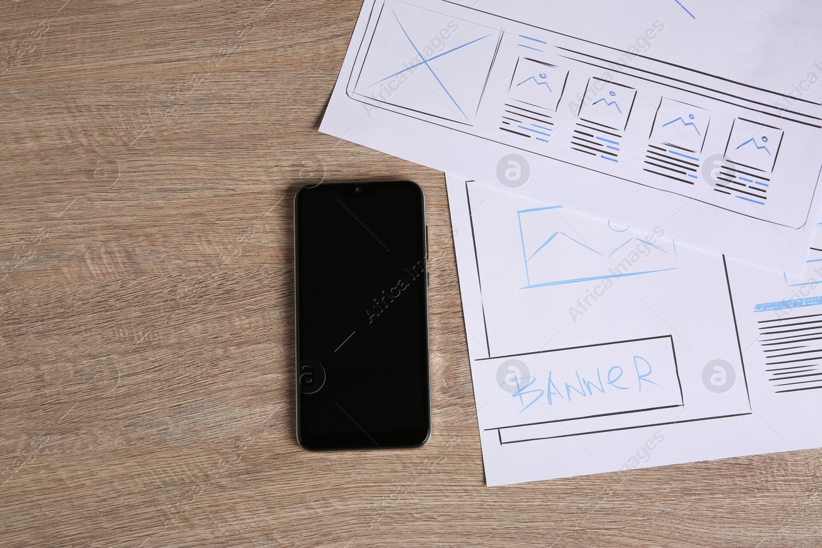 Photo of Developing UI design. Sketches of website wireframes and smartphone on wooden table, top view