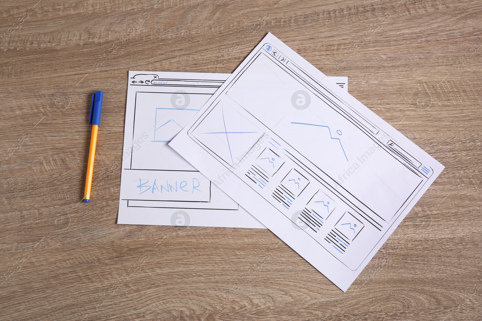 Photo of Developing UI design. Sketches of website wireframes and pen on wooden table, top view