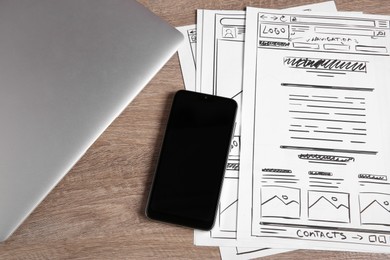 Developing UI design. Sketches of website wireframes, smartphone and laptop on wooden table, above view