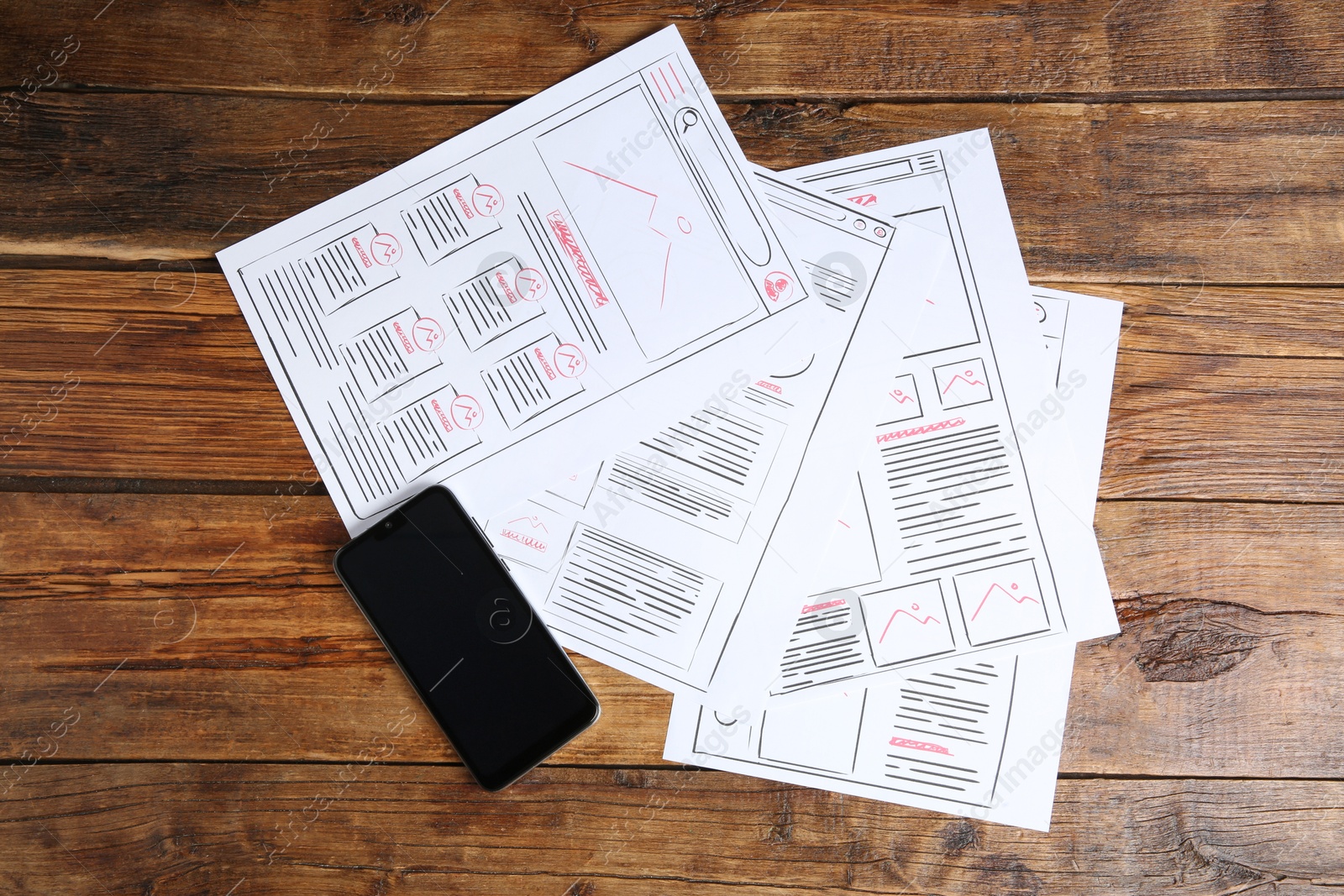 Photo of Developing UI design. Sketches of website wireframes and smartphone on wooden table, top view