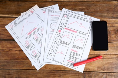 Photo of Developing UI design. Sketches of website wireframes, felt pen and smartphone on wooden table, top view