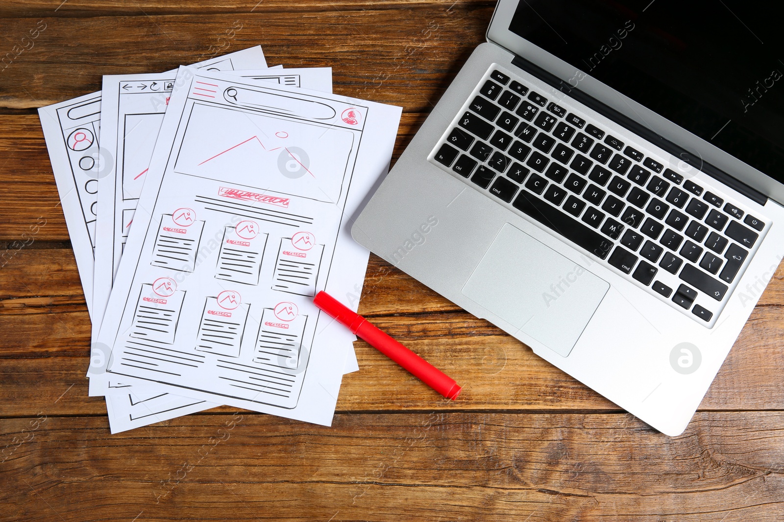 Photo of Developing UI design. Sketches of website wireframes, laptop and felt pen on wooden table, top view