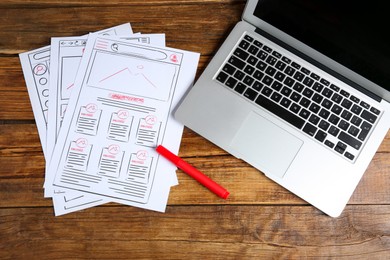 Developing UI design. Sketches of website wireframes, laptop and felt pen on wooden table, top view