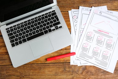 Photo of Developing UI design. Sketches of website wireframes, laptop and felt pen on wooden table, top view