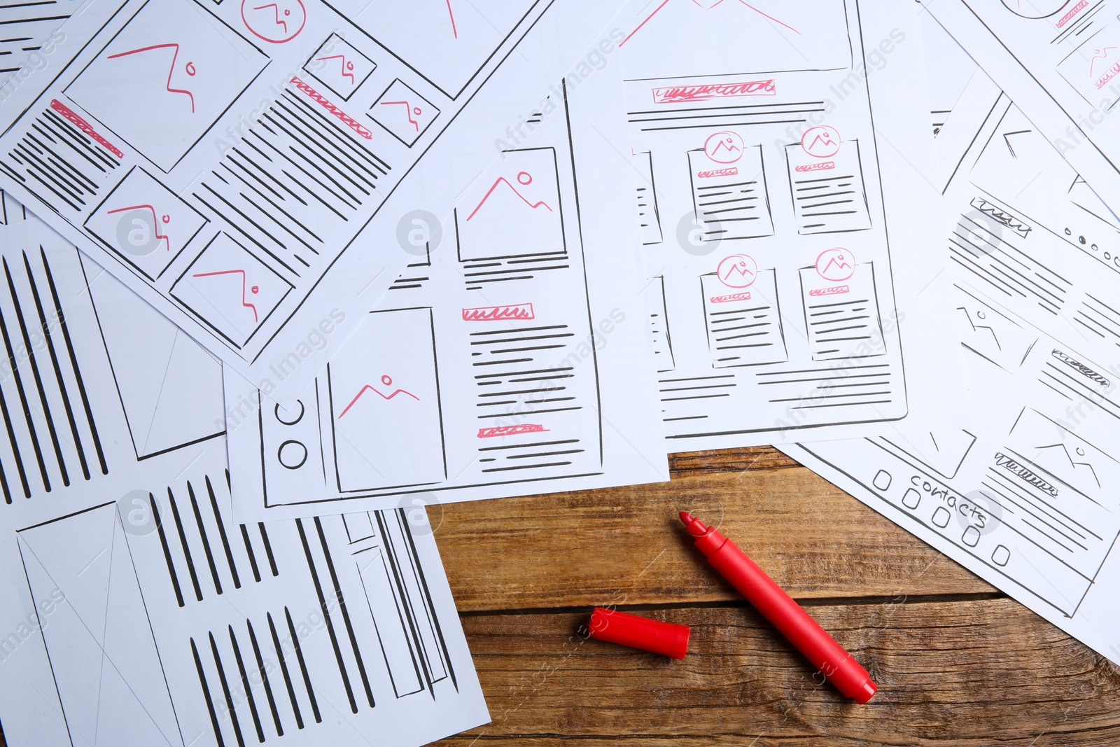 Photo of Developing UI design. Sketches of website wireframes and felt pen on wooden table, top view