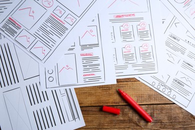 Developing UI design. Sketches of website wireframes and felt pen on wooden table, top view