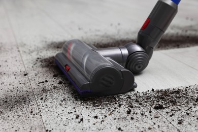 Photo of Cleaning floor with cordless vacuum cleaner indoors, closeup