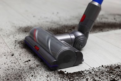 Photo of Cleaning floor with cordless vacuum cleaner indoors, closeup