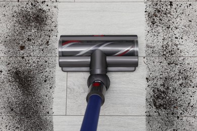 Photo of Cleaning floor with cordless vacuum cleaner indoors, top view