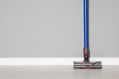 Photo of One cordless vacuum cleaner near grey wall indoors. Space for text