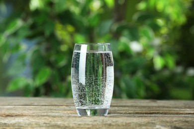 Photo of Soda water in glass on wooden table outdoors