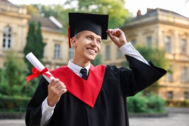 Photo of Happy student with diploma after graduation ceremony outdoors