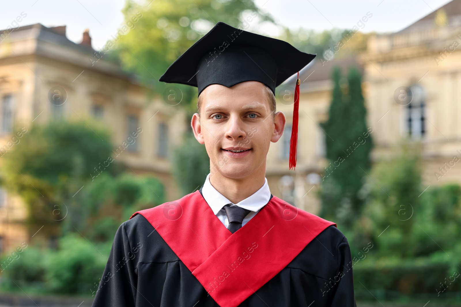 Photo of Graduation ceremony. Smiling student in academic dress outdoors