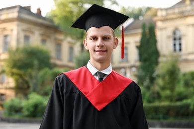 Photo of Graduation ceremony. Smiling student in academic dress outdoors