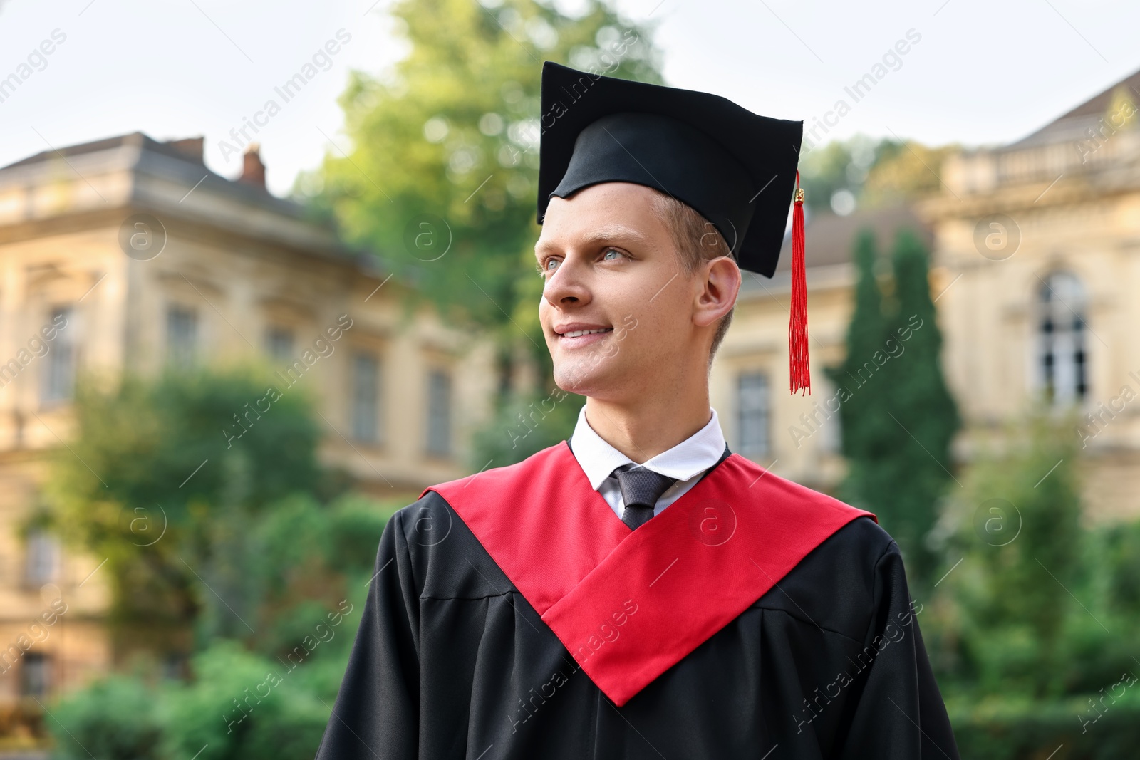 Photo of Graduation ceremony. Smiling student in academic dress outdoors