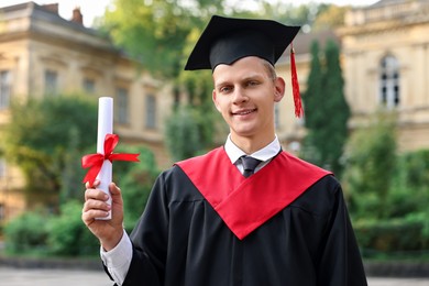 Photo of Student with diploma after graduation ceremony outdoors