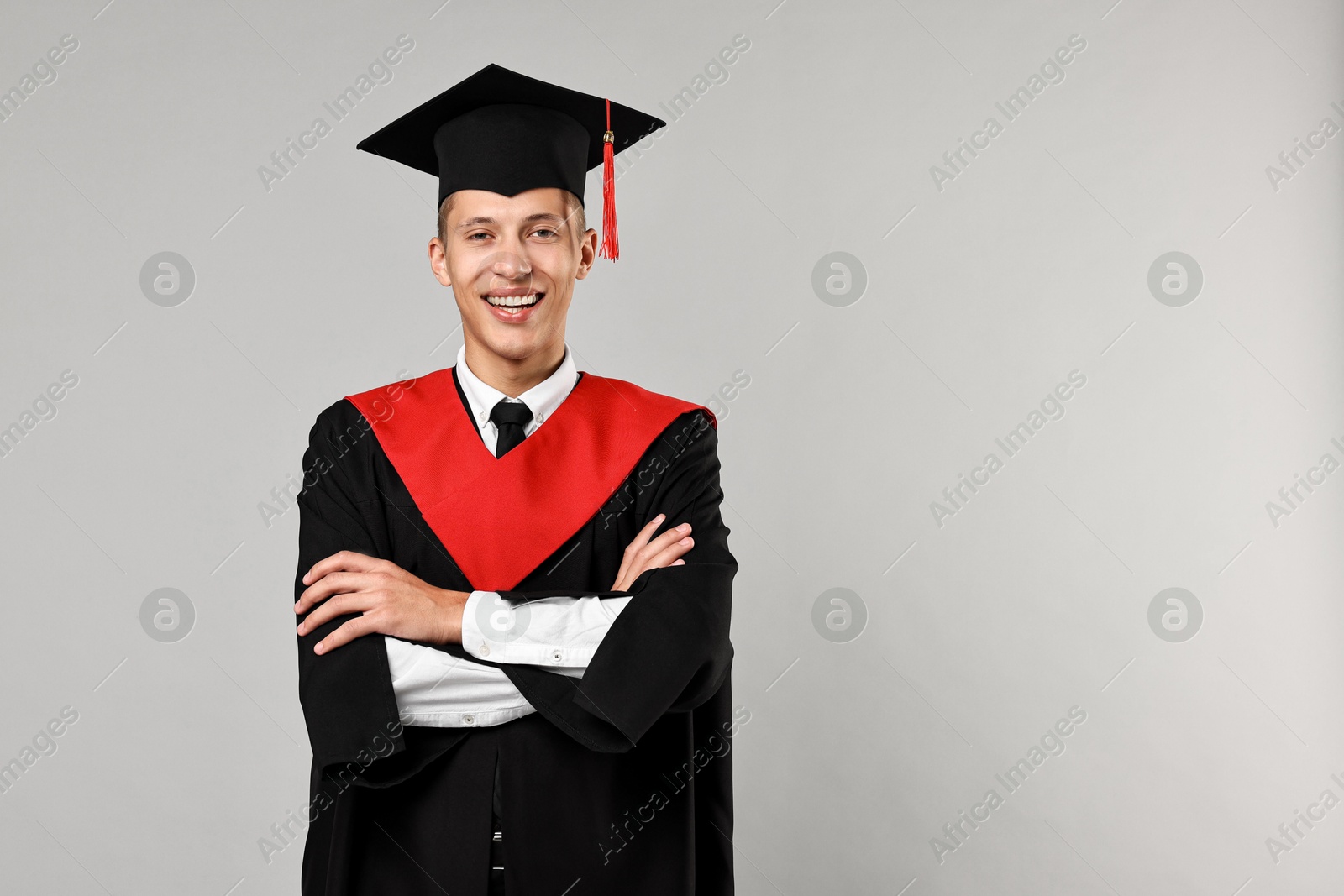 Photo of Happy student with crossed arms after graduation on grey background. Space for text