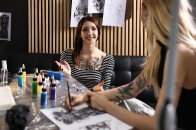 Tattoo artist discussing sketch with smiling client in salon