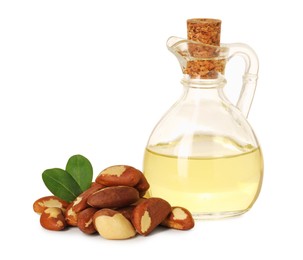 Photo of Tasty Brazil nuts and jug with oil isolated on white