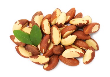 Photo of Tasty Brazil nuts and green leaves isolated on white, top view