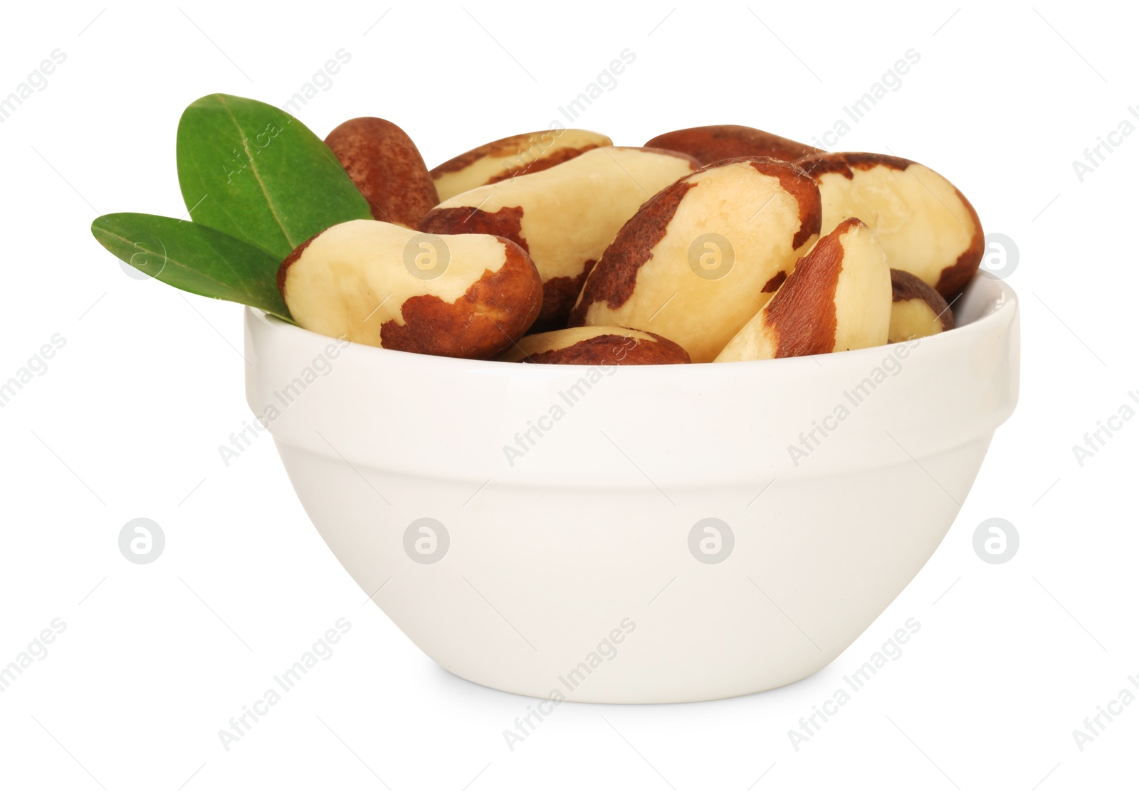 Photo of Tasty Brazil nuts and green leaves in bowl isolated on white