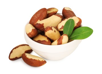 Photo of Tasty Brazil nuts and green leaves in bowl isolated on white