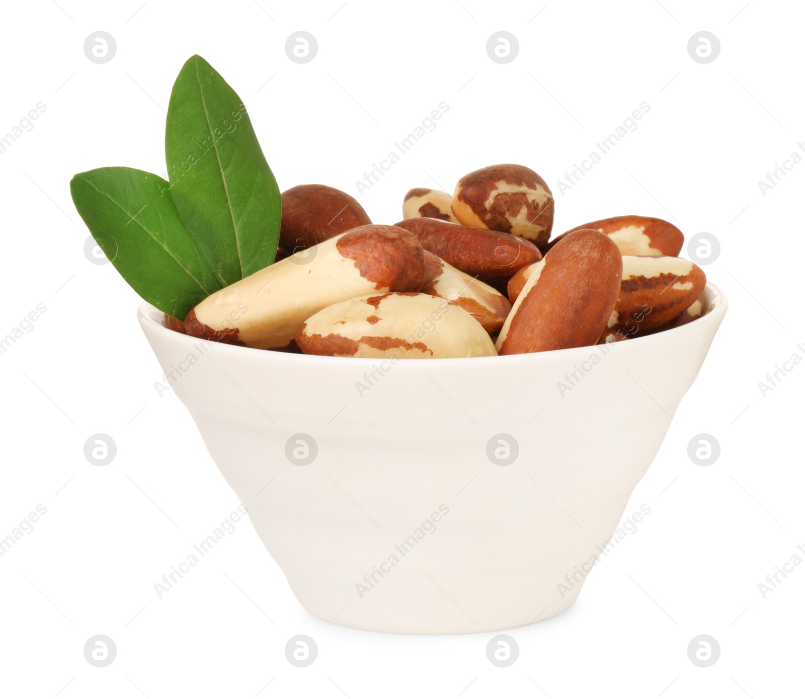 Photo of Tasty Brazil nuts and green leaves in bowl isolated on white