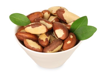 Photo of Tasty Brazil nuts and green leaves in bowl isolated on white