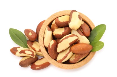 Photo of Tasty Brazil nuts in bowl and green leaves isolated on white, top view