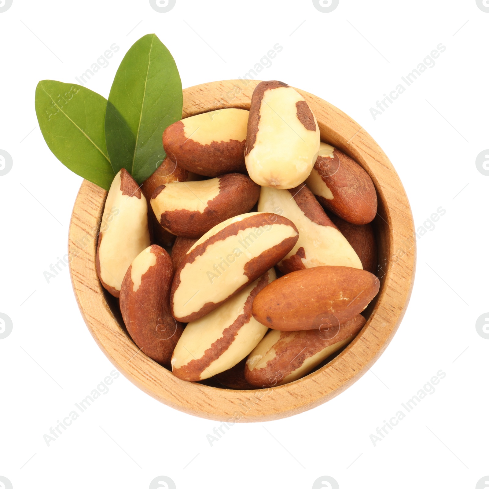 Photo of Tasty Brazil nuts and green leaves in bowl isolated on white, top view