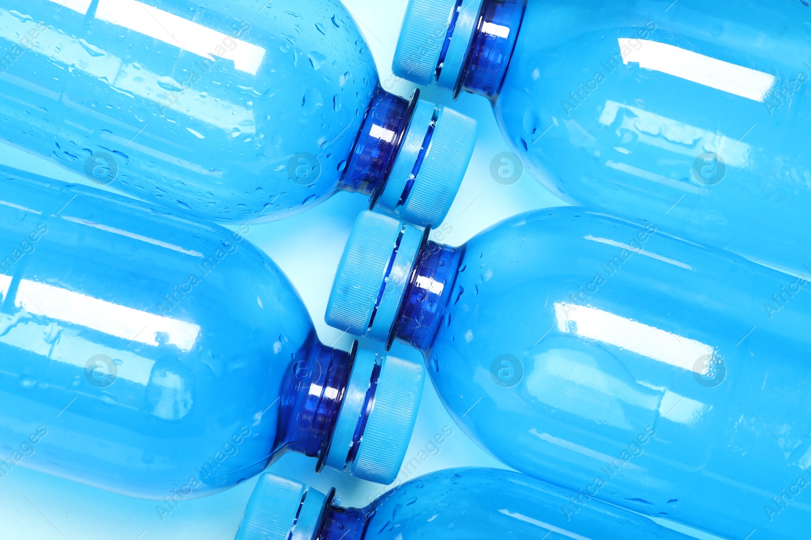 Photo of Many plastic bottles on light background, top view