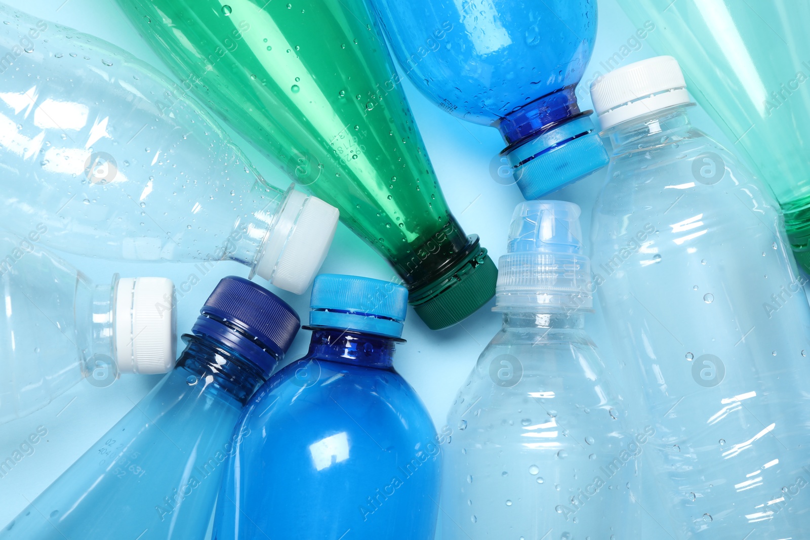 Photo of Many plastic bottles on light background, top view