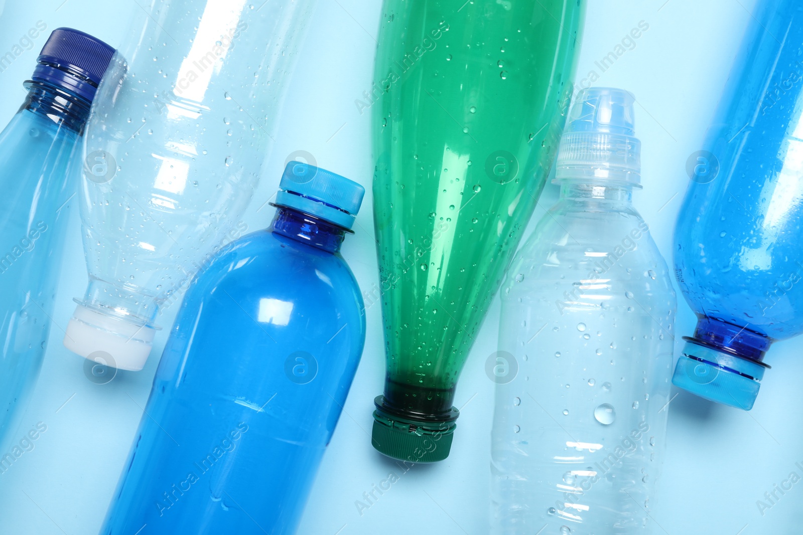 Photo of Many plastic bottles on light background, top view