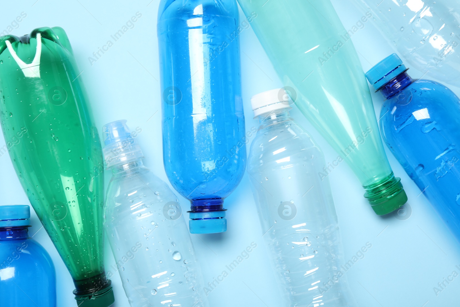 Photo of Many plastic bottles on light background, top view