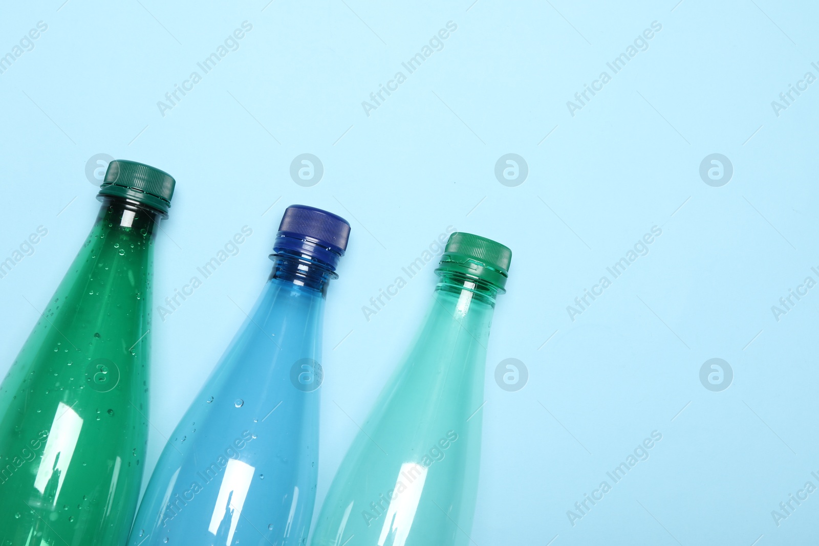 Photo of Plastic bottles on light background, top view. Space for text